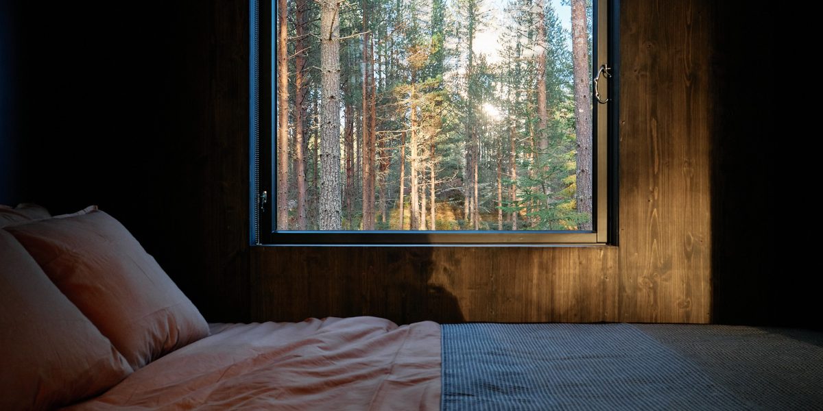 Digital detox cabin bedroom with natural light, organic linens, and curated book collection