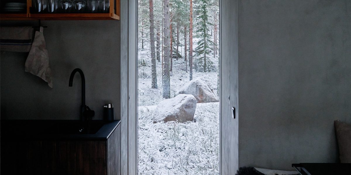 Modern minimalist cabin interior with Nordic design touches - kitchen view with large forest-facing windows